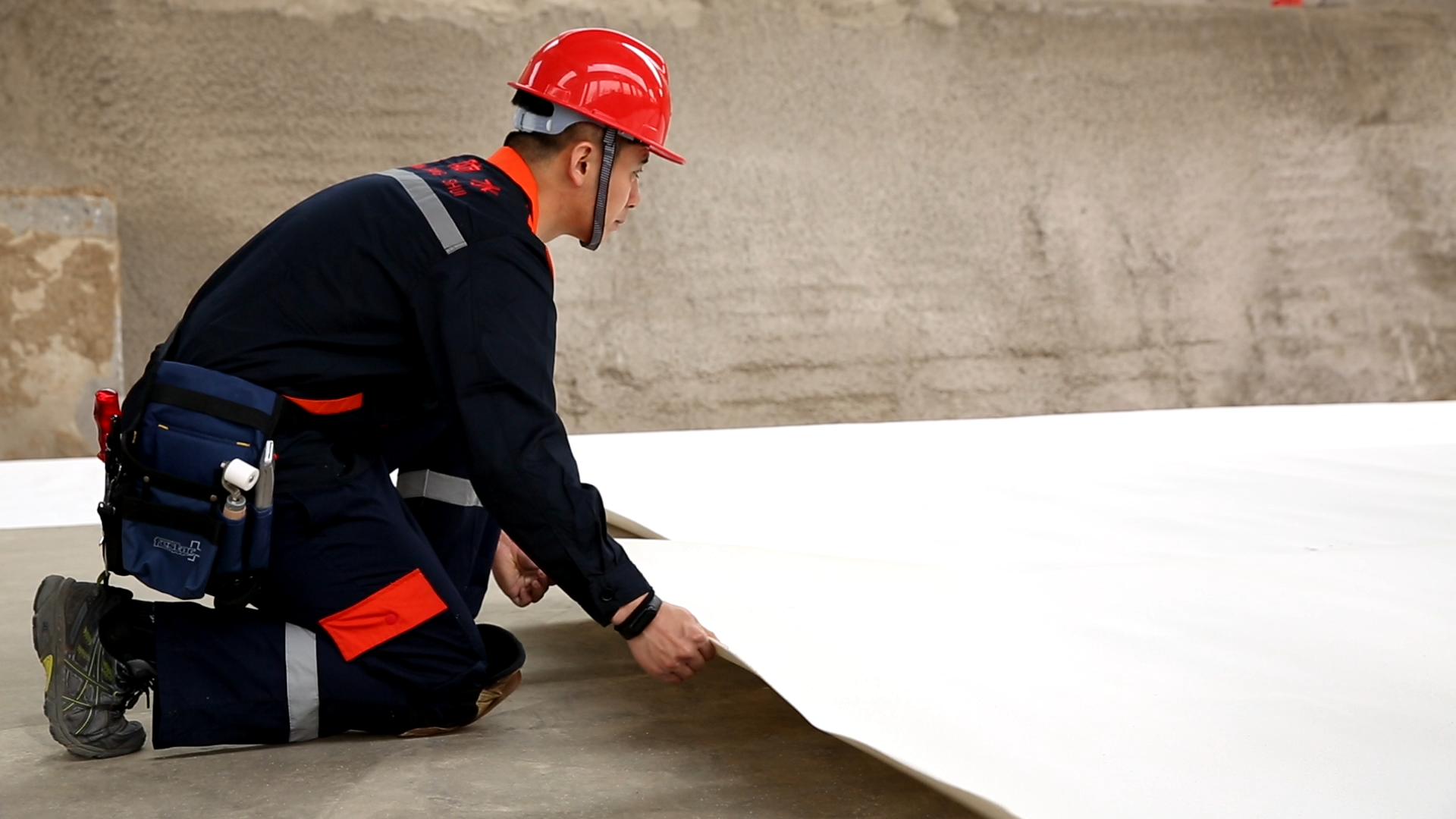Installer positioning a white HDPE waterproofing membrane